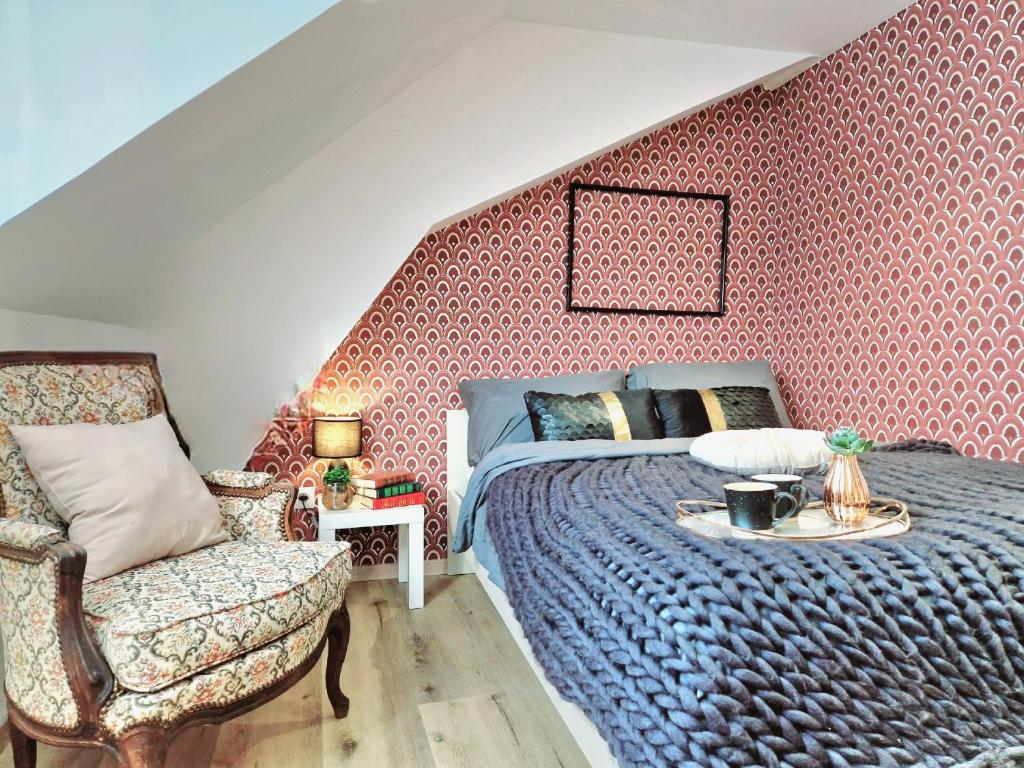 a bedroom with a bed and a chair and a table at L'élémentaire, appartement chic et central in Mulhouse