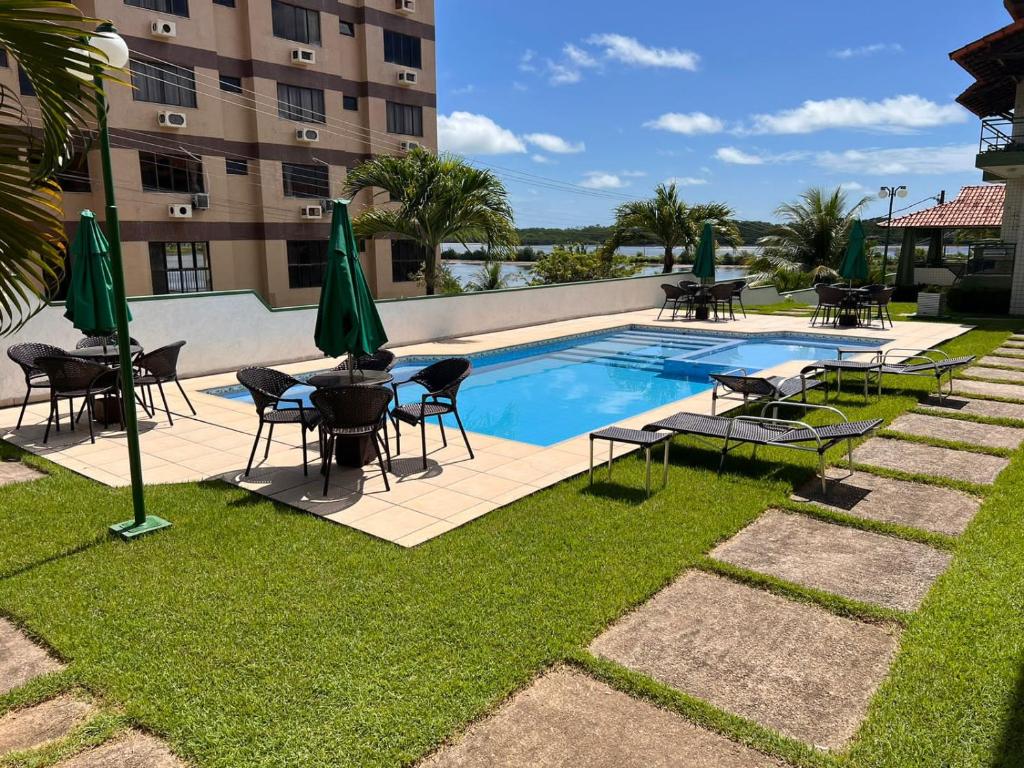 a swimming pool with tables and chairs next to a building at Apartamento Mobiliado cozinha completa na Praia in Salinópolis