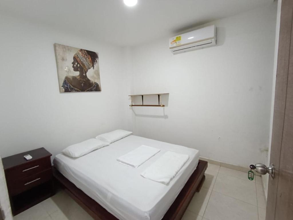 um pequeno quarto branco com uma cama e uma ventoinha em Cabaña la Isla-Coveñas em Coveñas