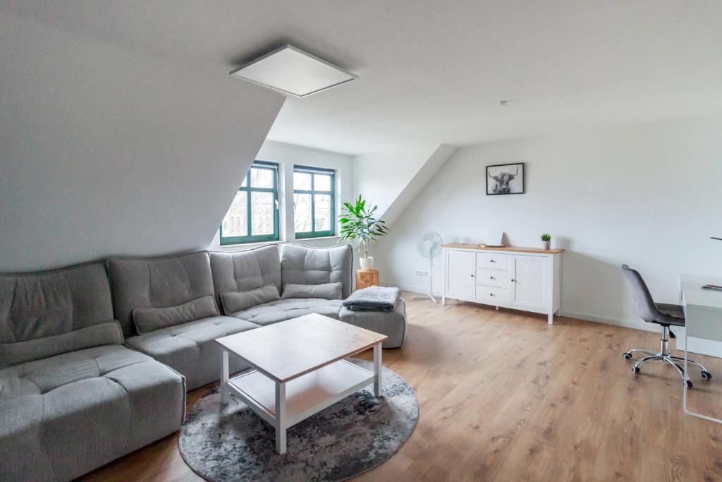 uma sala de estar com um sofá e uma mesa em Ferienwohnung "Kapellmeister" mit Klimaanlage in allen 4 Schlafbereichen, großes Wohnzimmer mit Smart TV und Big Sofa em Magdeburg