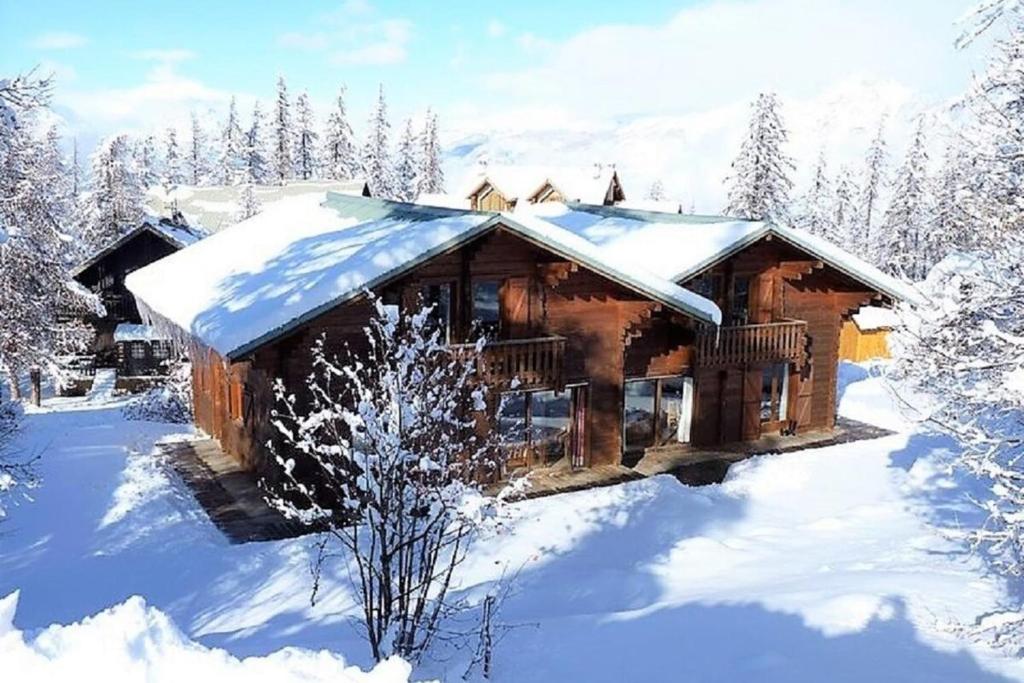 una cabaña de madera en la nieve con nieve en CASA-Forêt Blanche splendid chalet 13p, en Risoul
