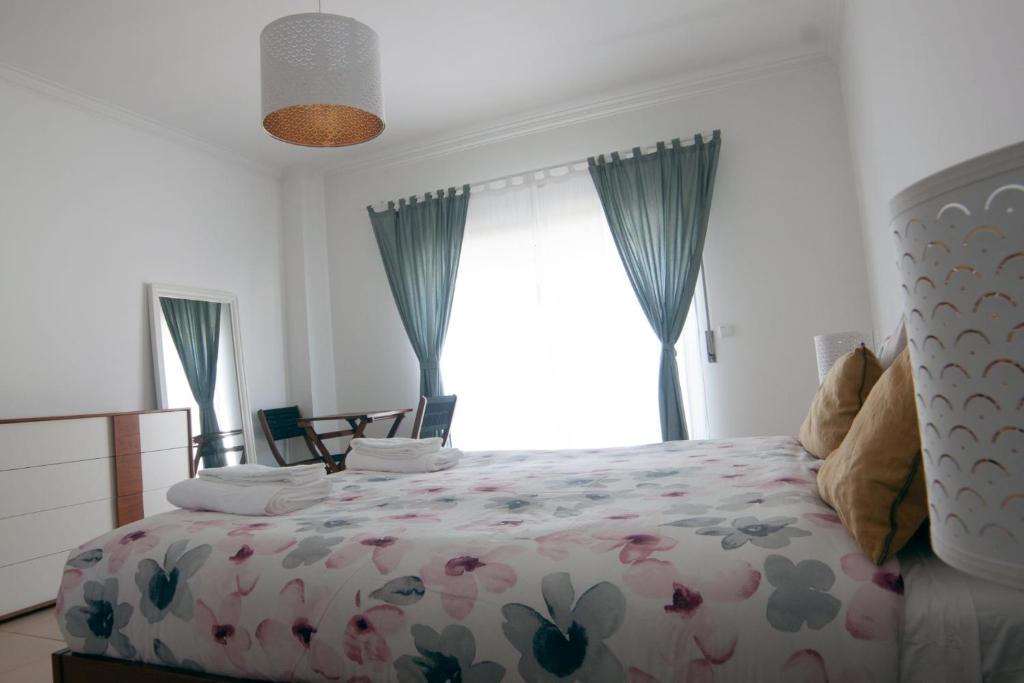 1 dormitorio con 1 cama con colcha de flores en InTune Peniche Property, en Peniche