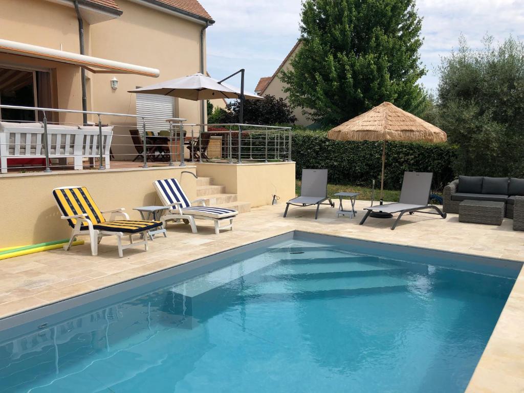 einen Pool mit Stühlen, einem Tisch und einem Sonnenschirm in der Unterkunft 3 Chambres chez particulier pour les 24h du Mans et Jeux olympiques 2024 in Le Mans