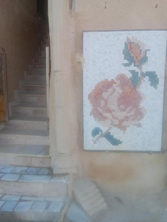 een schilderij van een bloem op een muur naast de trap bij Mosaic House 24 in Raoued