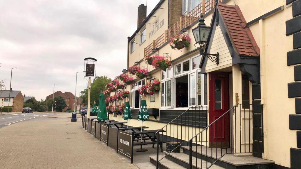 a building with tables and chairs on a street at The Poacher in Stevenage
