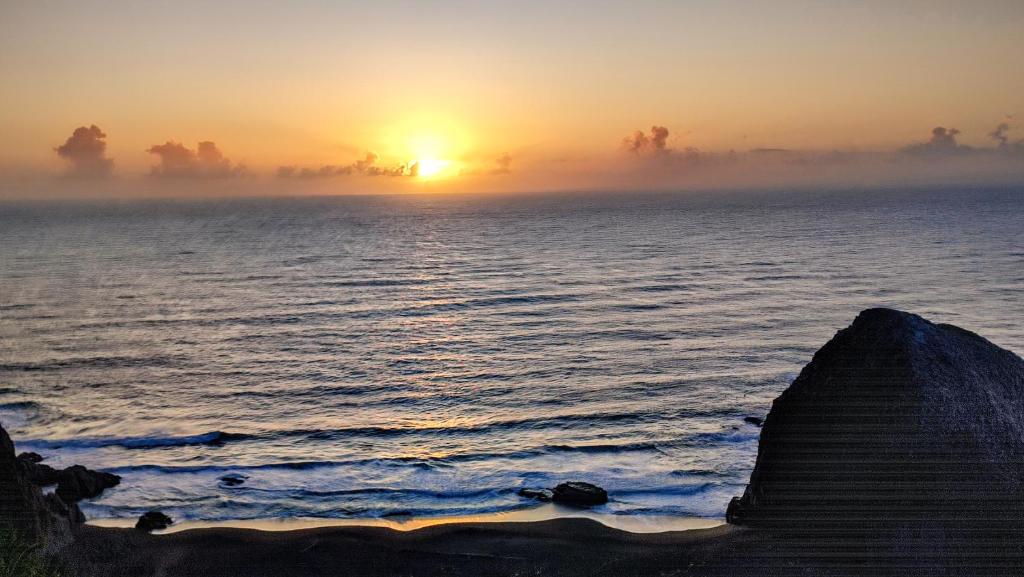 um nascer do sol sobre o oceano com o sol à distância em Hotel Casa Puccllana em Constitución