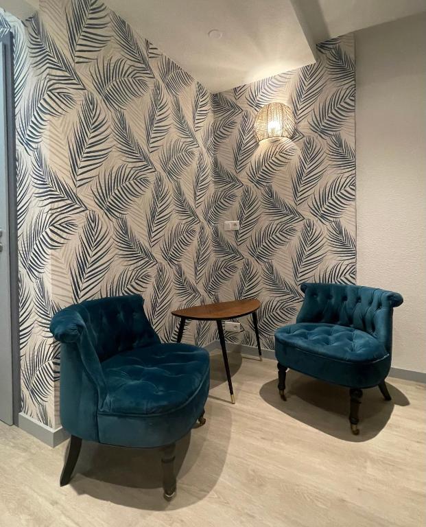 2 chaises et une table dans une chambre avec un mur dans l'établissement Gîte des oiseaux, à Colmar