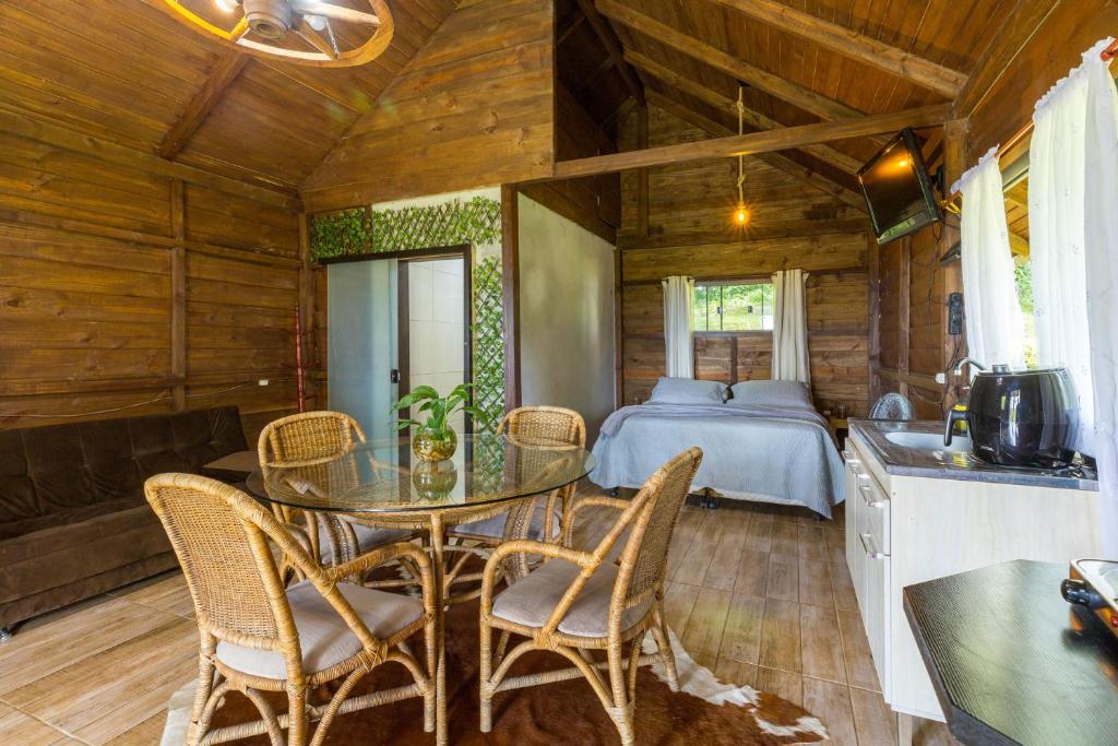 ein Esszimmer mit einem Tisch, Stühlen und einem Bett in der Unterkunft Excelente chale com bela vista em Rio do Sul SC in Rio do Sul
