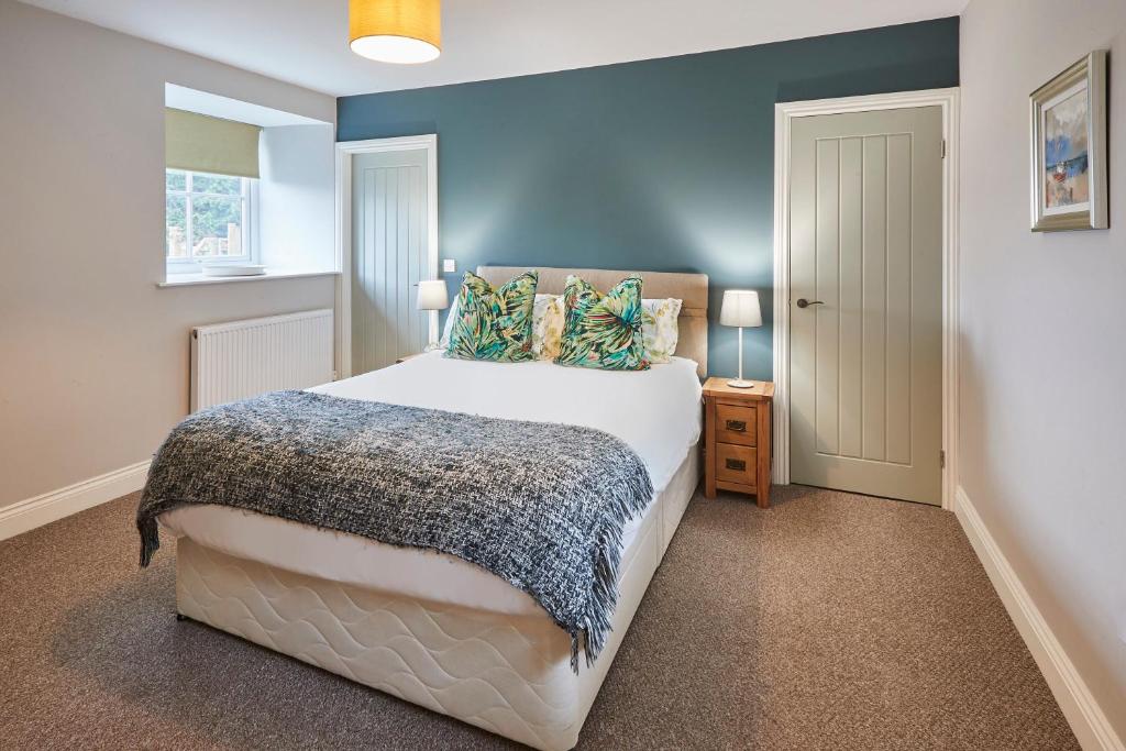 a bedroom with a large bed with blue walls at Host & Stay - Fenwick Village Hall in Fenwick
