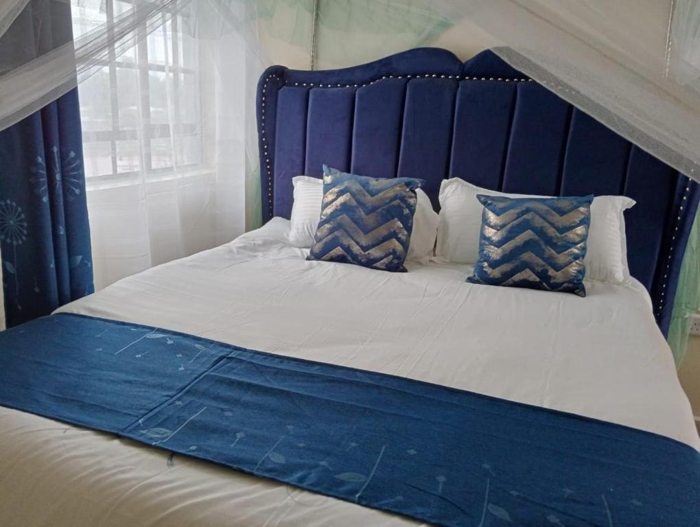 Bett mit blauem Kopfteil und Kissen in der Unterkunft Bomet studio/bedsitter next to Chelsa Academy in Bomet