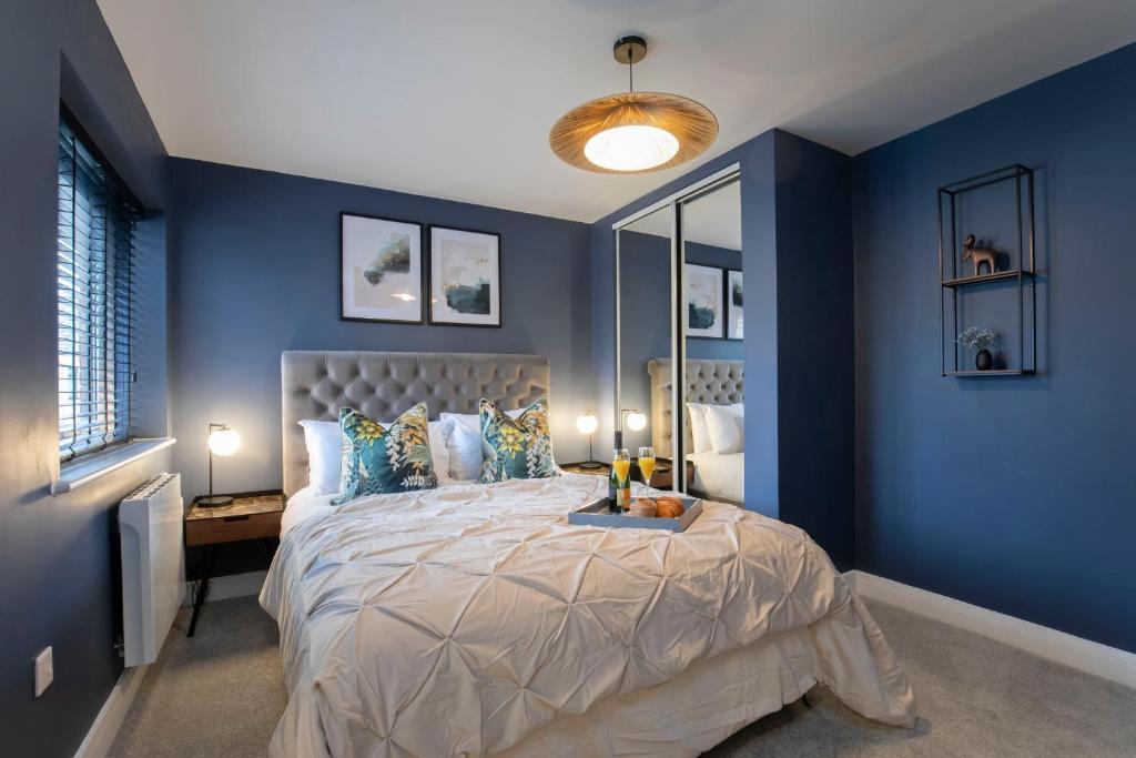 a bedroom with blue walls and a large bed at Elliot Oliver - Exquisite Two Bedroom Apartment With Garden, Parking & EV Charger in Cheltenham