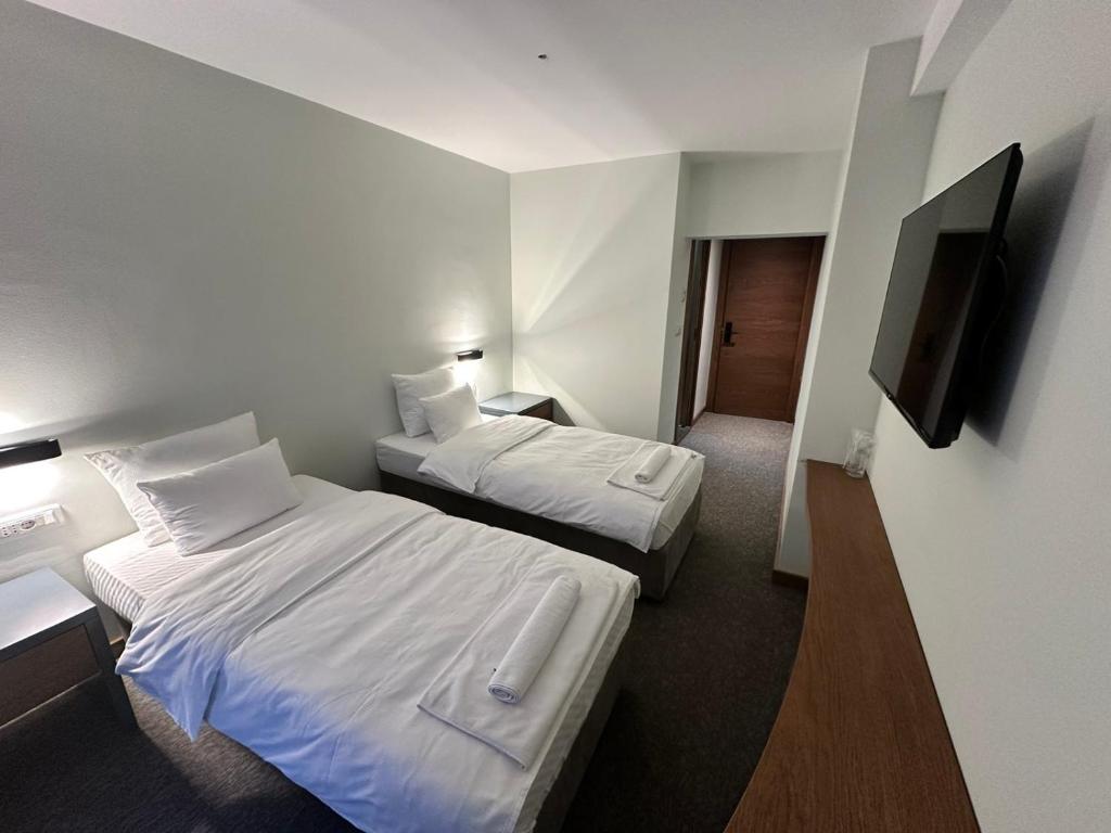 a hotel room with two beds and a flat screen tv at Hotel Pljevlja in Pljevlja