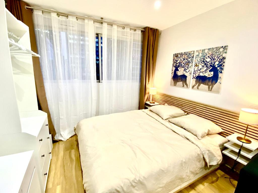 ein Schlafzimmer mit einem großen Bett und einem Fenster in der Unterkunft Charmant appartement à La Défense - Très proche de Paris - A côté des transports in Courbevoie
