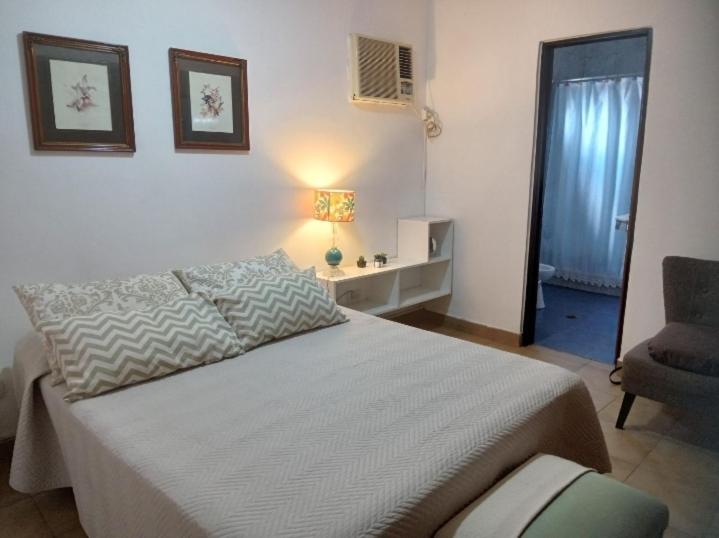 a bedroom with a large bed and a chair at La Toscana - Actum in San Miguel de Tucumán