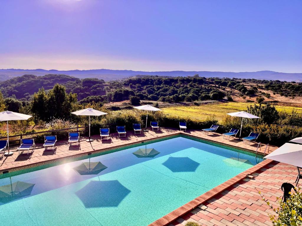 uma grande piscina com cadeiras e guarda-sóis em Agriturismo Sa Pigalva em Tula