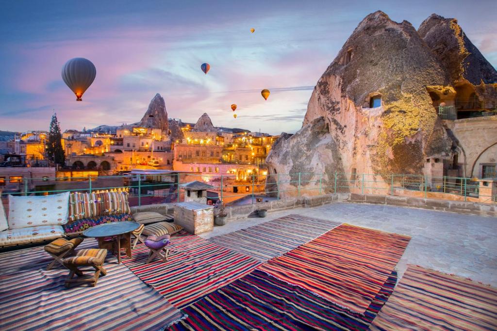 een groep heteluchtballonnen die over een stad vliegen bij Terra Cave Hotel in Goreme