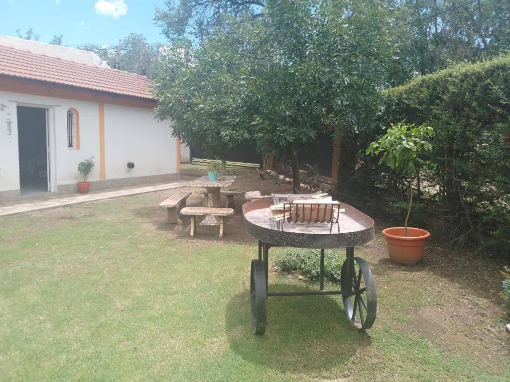 a wheelbarrow in a yard with a table and benches at El Marino in Merlo