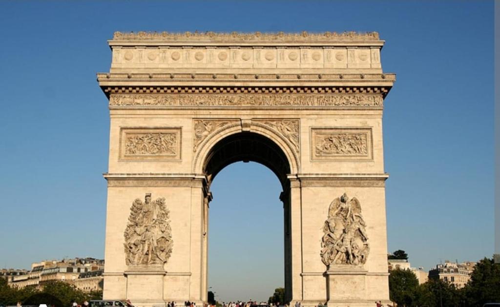 a large monument with an arch in a city at Arc de triomphe studio charme authentique in Paris