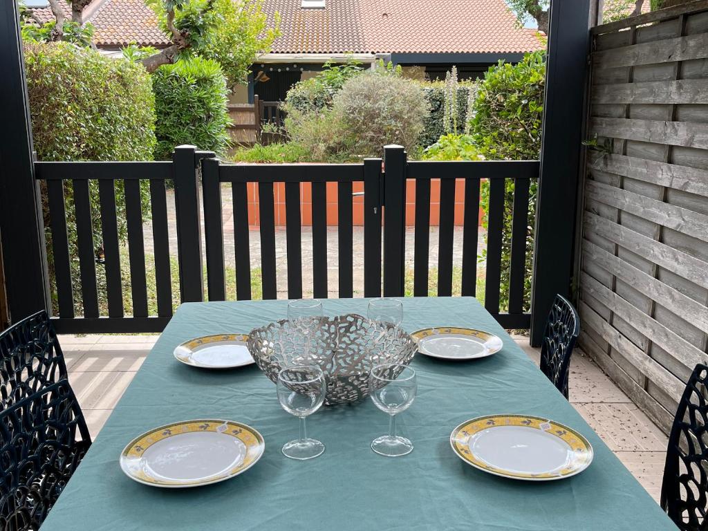 - une table bleue avec des assiettes et des verres à vin sur la terrasse dans l'établissement Charmant Pavillon à Argelès-sur-Mer avec Piscine, Terrasse et Parking - FR-1-732-23, à Argelès-sur-Mer