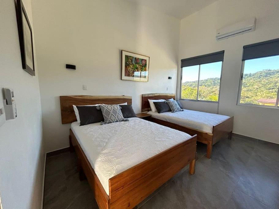 1 dormitorio con 2 camas y ventana grande en Casa Abundia - Caracoles Studio, en Carrillo
