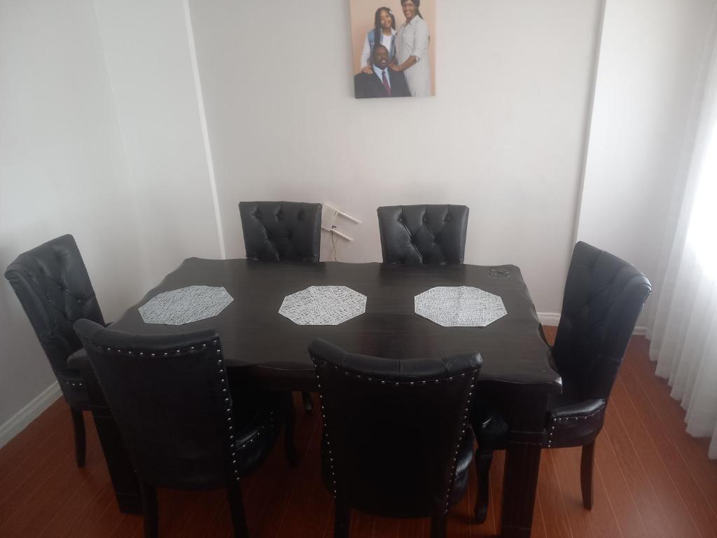 - une table à manger noire avec 4 chaises noires dans l'établissement Amreff Nyumbani villas, à Kitengela 
