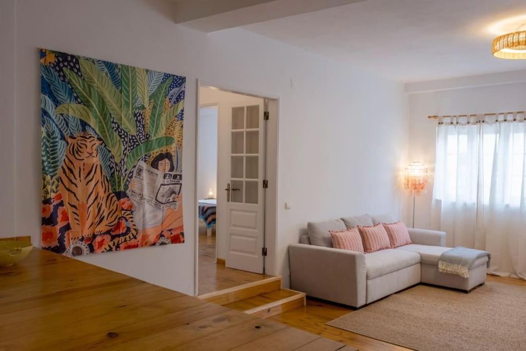 a living room with a couch and a painting on the wall at Apartamento Aires - Trafaria in Trafaria