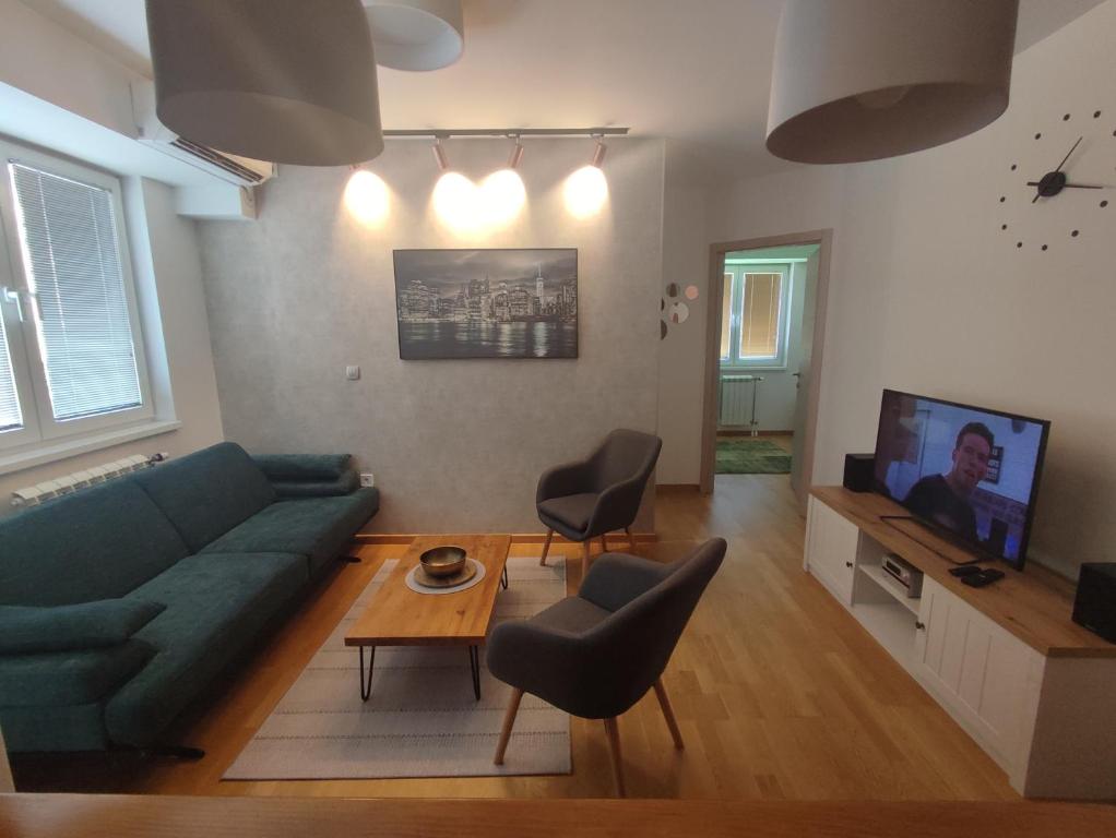 uma sala de estar com um sofá verde e uma televisão em Cozy Urban Apartment in Skopje! em Skopje
