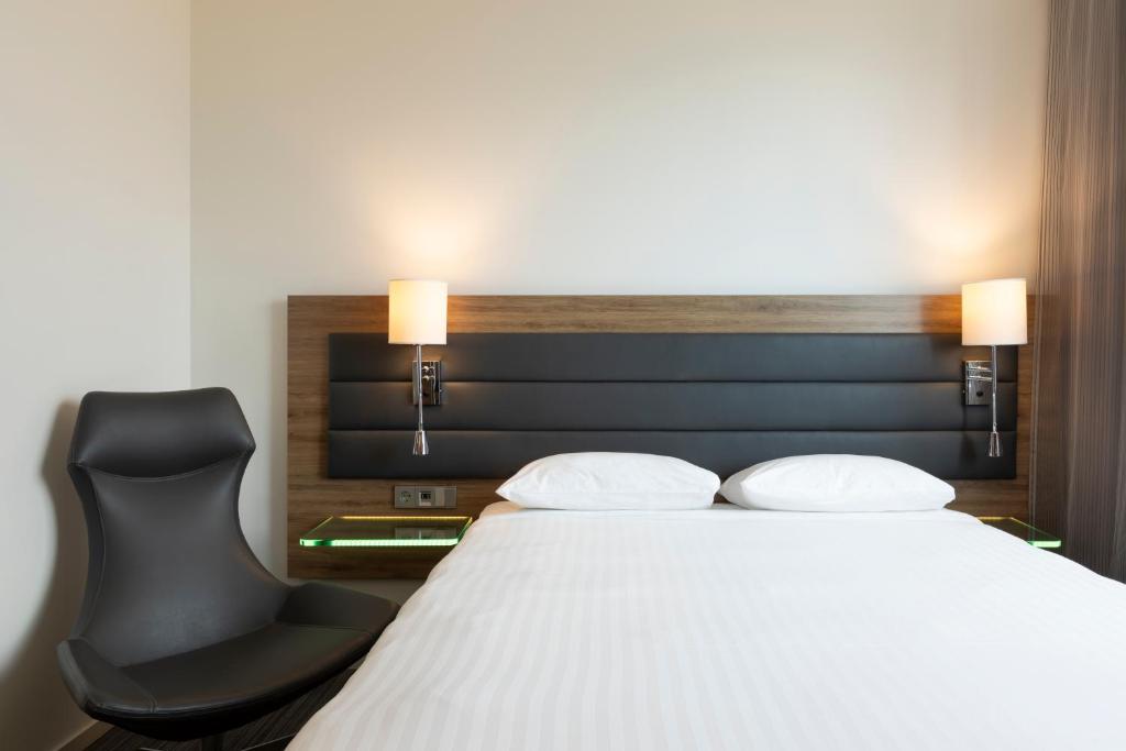 a bedroom with a bed and a black chair at Moxy Aberdeen Airport in Dyce