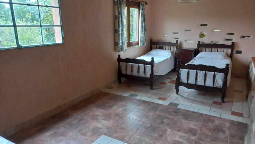 Habitación con 2 camas y suelo de baldosa. en Residencia zona sierras chicas (casa) El talar en Mendiolaza