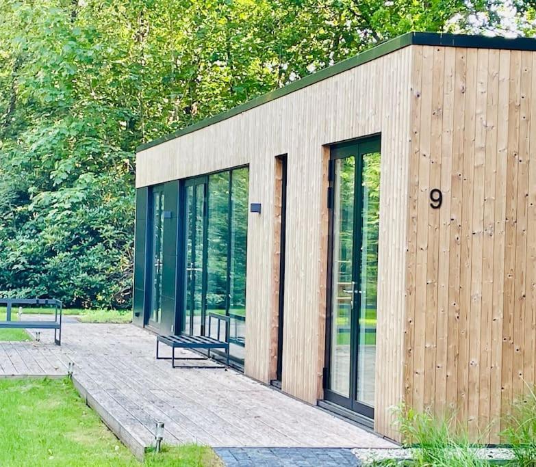 a small building with glass doors and a bench at Chalet goudmeer LUXURY AIRCO WIFI 3 bedrooms 2 bathrooms in Oosterwolde