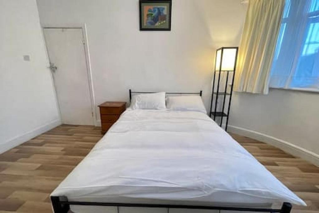 a bedroom with a bed with white sheets and a window at Twin Tranquility- Room in Leyton in London