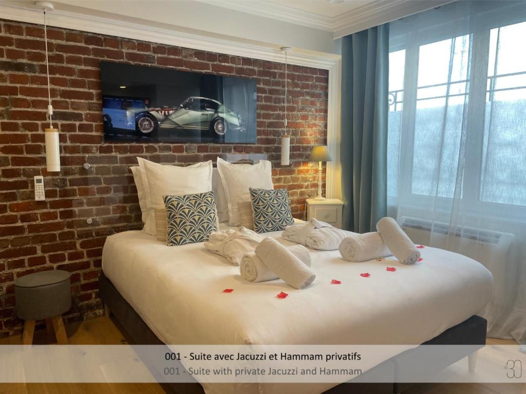 - une chambre avec un grand lit blanc et un mur en briques dans l'établissement Au 30, à Lille