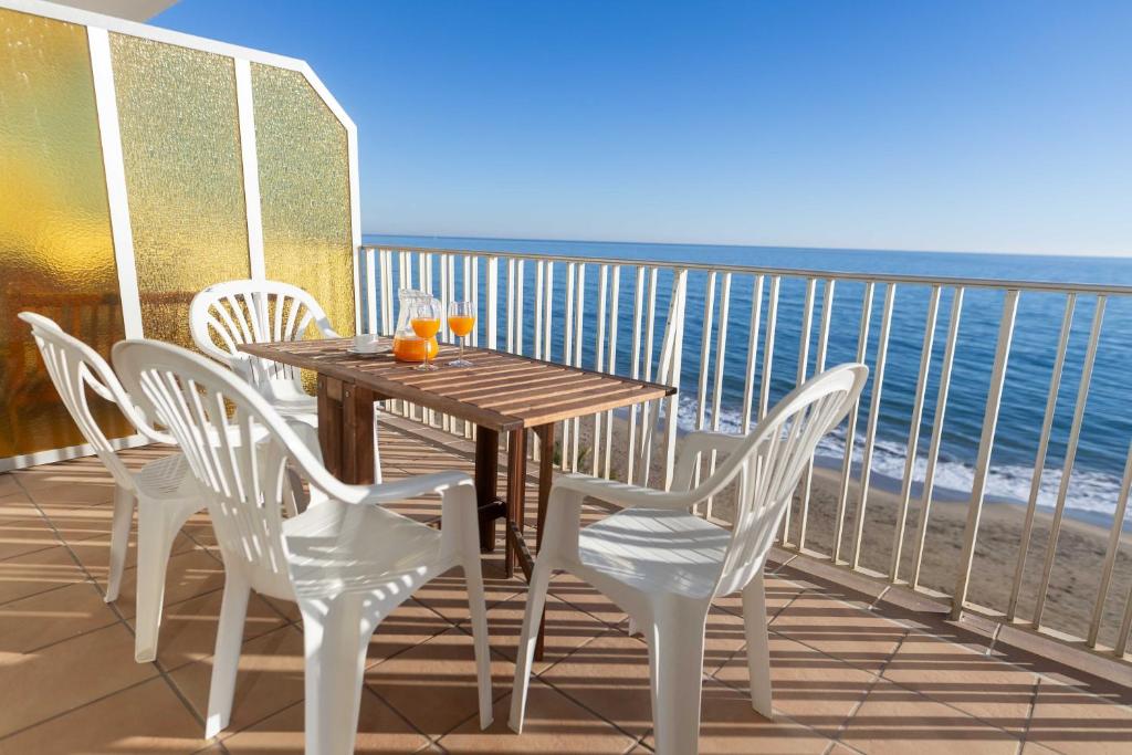 een tafel en stoelen op een balkon met uitzicht op de oceaan bij Suitur apartamento frente a la playa de calafell in Calafell