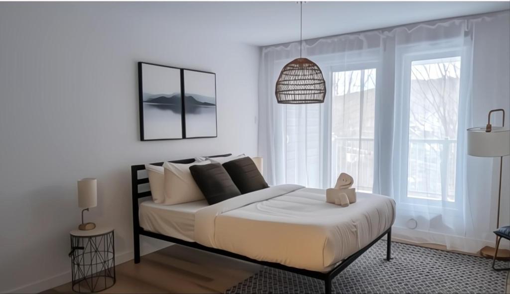 a bedroom with a bed with white sheets and pillows at L’espace Mysa - Studio Lugna in Mont-Tremblant