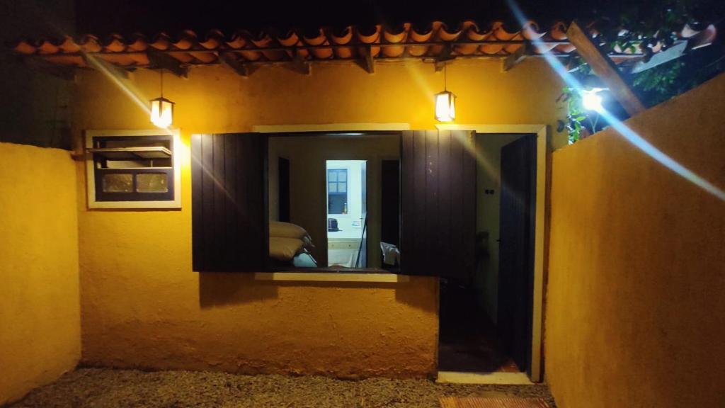 卡波布里奧的住宿－Casinha do Peró，一面镜子,一面是黄色建筑的一面,上面有灯光