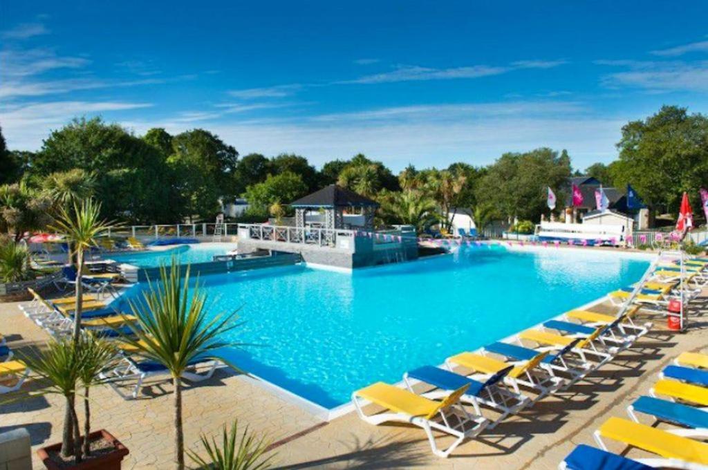 a large swimming pool with yellow lounge chairs at mobil home 3 chambres 152 in Pont-Aven