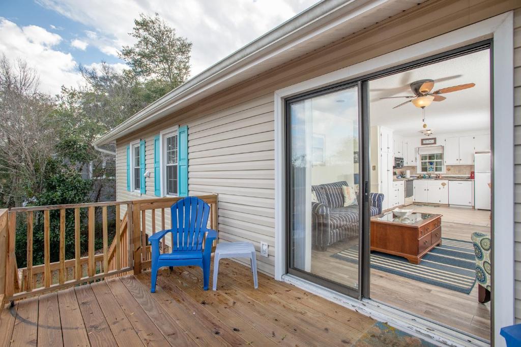 un porche con una silla azul y una puerta corredera de cristal en Close Enough home, en Emerald Isle