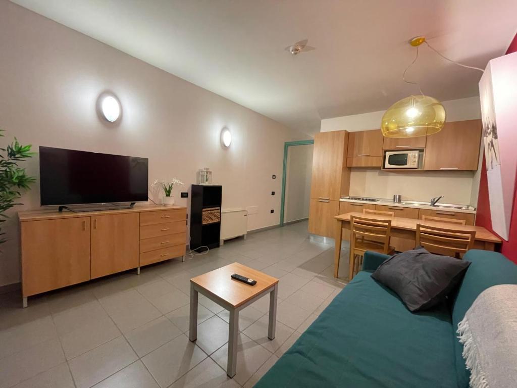 a living room with a blue couch and a kitchen at Attico Villaggio Olimpico Sestriere in Sestriere