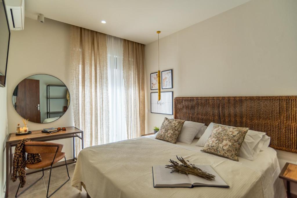 a bedroom with a bed with a table and a mirror at Samos Tropic Apartments in Ríva