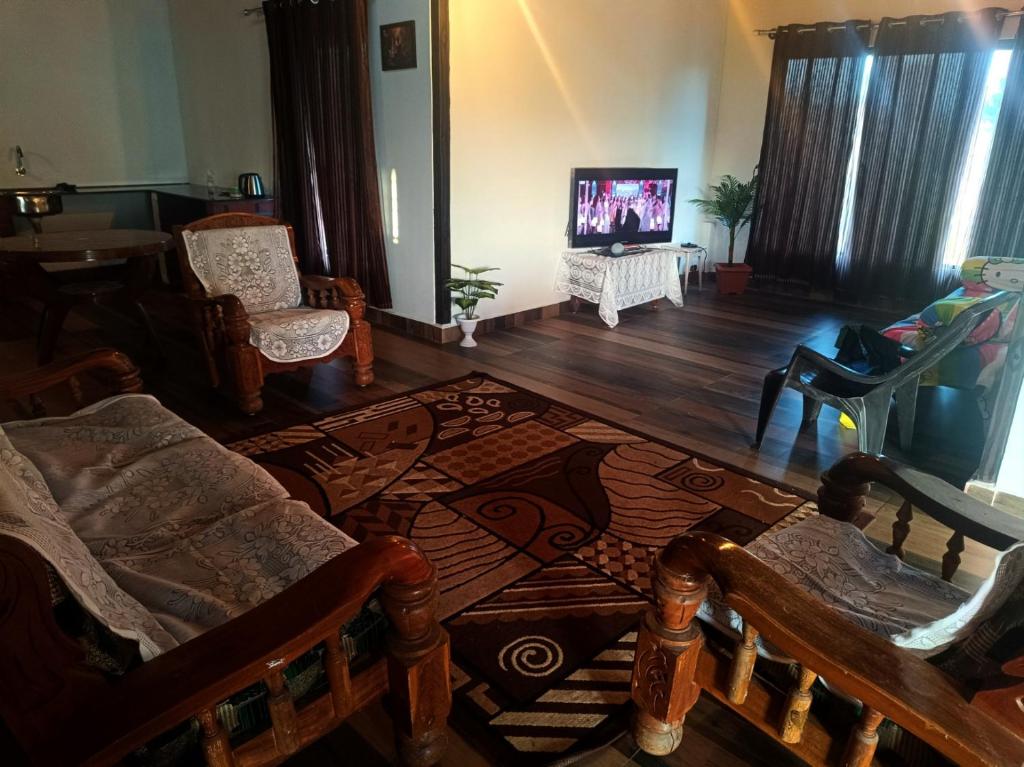 a living room with a couch and a tv at Jishi Homestay in Madikeri