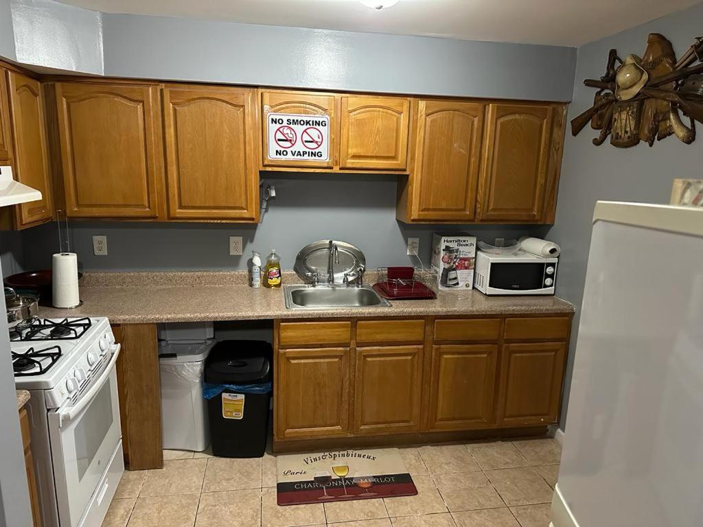 a kitchen with wooden cabinets and a sink and a refrigerator at Guest House 3 BEDROOM 2 Bathrooms 5 MINS TO EWR NEWARK AIRPORT 4 MINS TO PENN STATION in Newark