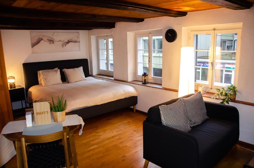 a bedroom with a bed and a chair and windows at MANY'S historical city central APARTMENTS in Zurich