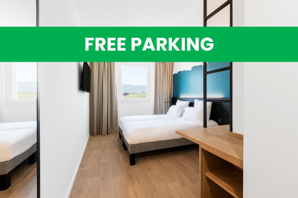 B&B HOTEL Nyon في نيون: غرفة في الفندق مع سرير ومكتب مع مواقف مجانية للسيارات بالنص