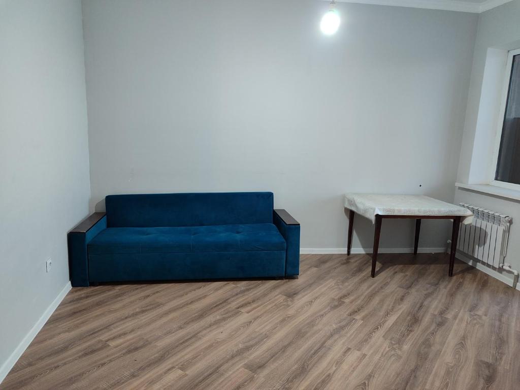 a blue couch in a room with a table at Дюсембекова 44/2 in Karagandy