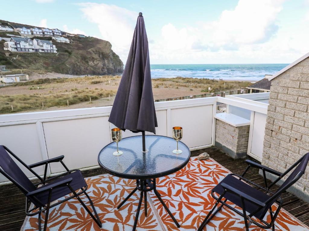 a table with an umbrella on a balcony with the ocean at 16 Seaspray in Truro