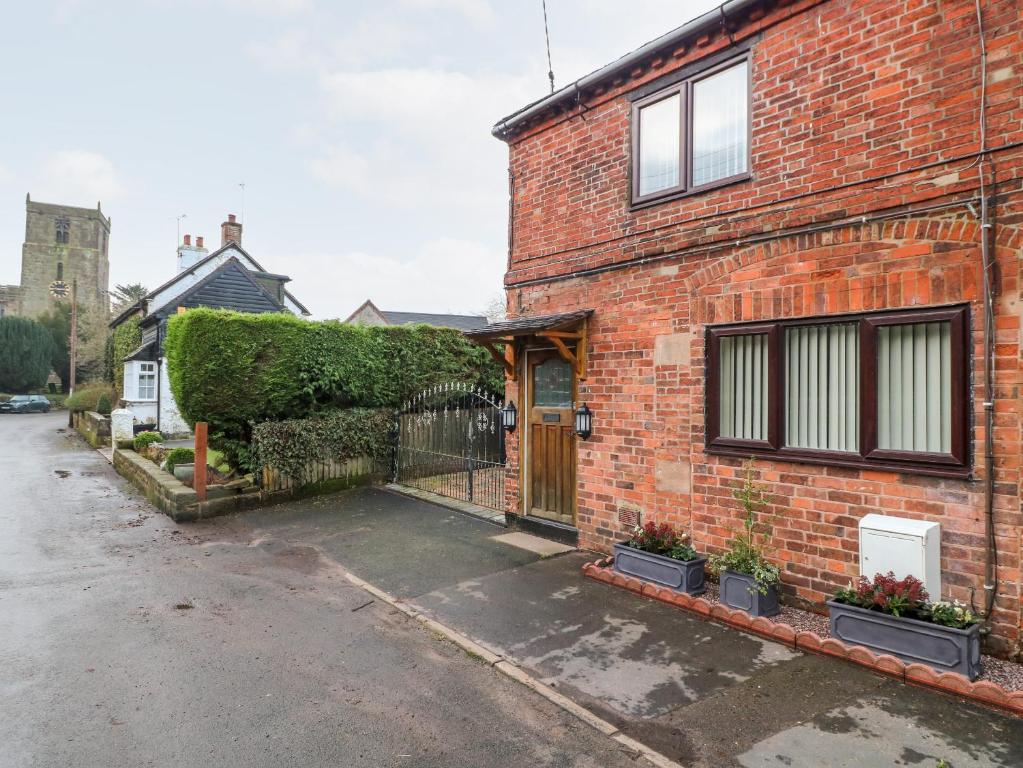 a brick house with a gate in front of it at 8 Church Lane in Checkley