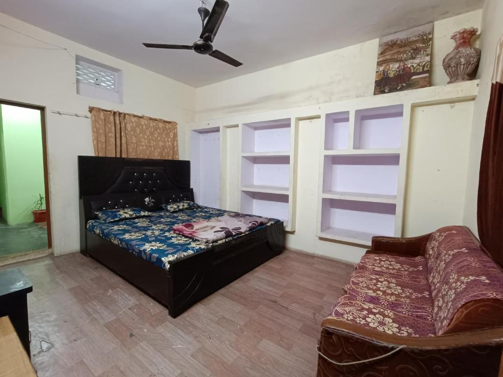 een slaapkamer met een bed en een bank erin bij JPM Hostel in Varanasi