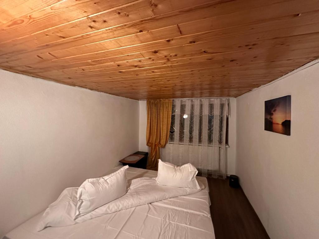 a bed in a room with a wooden ceiling at Pensiunea Stefan in Durău