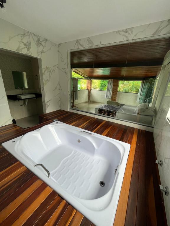 baño con una gran bañera blanca y ventana en Pousada Cantim de BH en Venda Nova