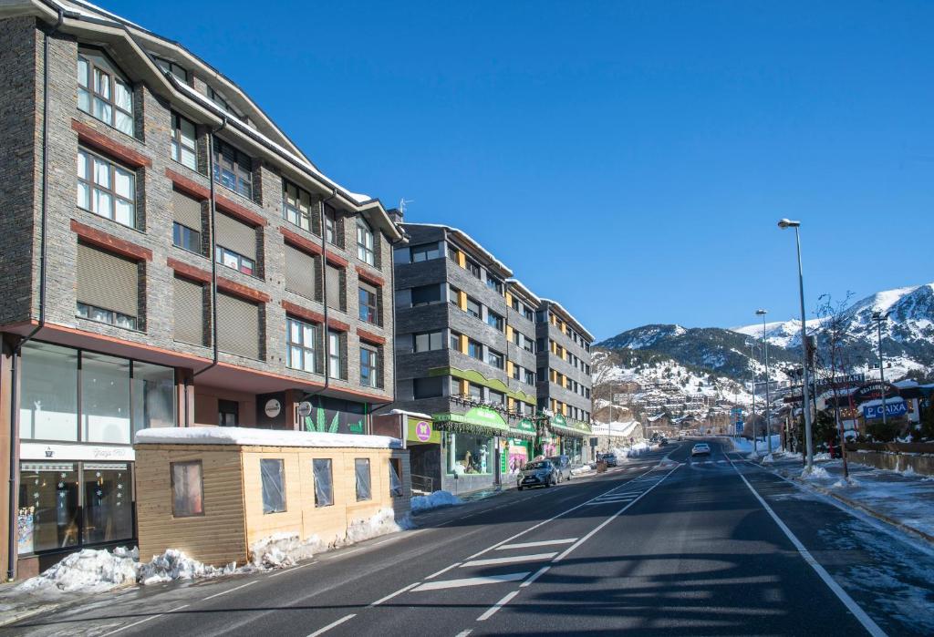 uma rua vazia numa cidade com edifícios e montanhas em Pierre & Vacances La Merceria em El Tarter